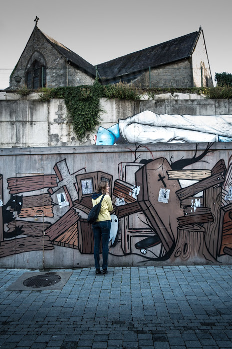 Over time, various artists have provided layers of meanings along this street in Kilkenny, Ireland. Small windows in the graveyard painting let viewers select their own vantage points and help them view what's happening on the other side of the wall. The photographer (Frank Daly) selected his own frame of reference, capturing an entertaining yet  chilling portrayal of the phenomenon of Western burial.